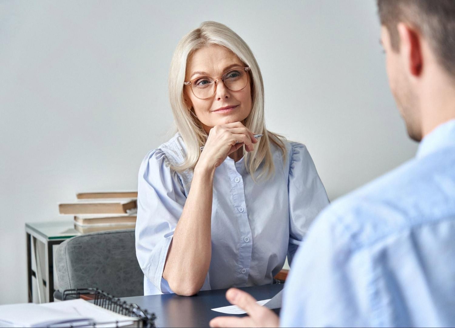 HR consultant in glasses interviewing a candidate across an office desk in the UAE