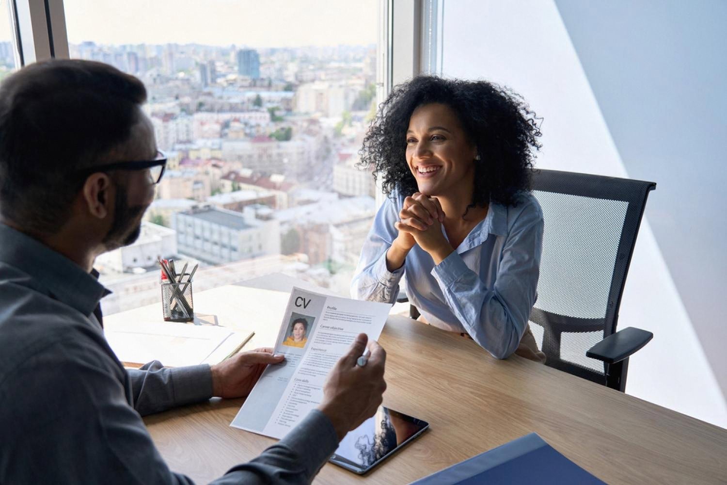 Smiling candidate meeting an HR recruiter who is reviewing her CV in a Dubai office
